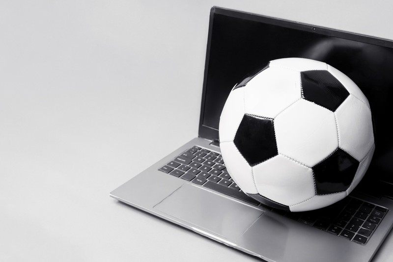 Football on Laptop Against Grey Background