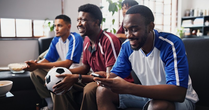 Man Using Phone Watching Football with Friends